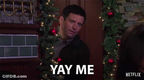 A Man With A Christmas Tree In The Background Says Yay Me GIF
