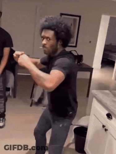 A Man With A Cigarette In His Mouth Is Dancing In A Living Room GIF