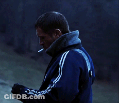 A Man With A Cigarette In His Mouth Wearing A Blue Adidas Jacket GIF