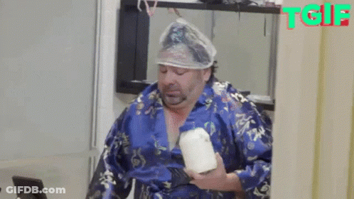 A Man With A Condom On His Head Is Holding A Candle . GIF