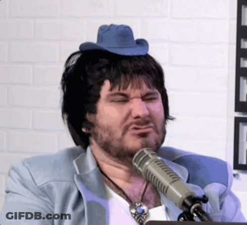 A Man With A Cowboy Hat On His Head Is Talking Into A Microphone GIF
