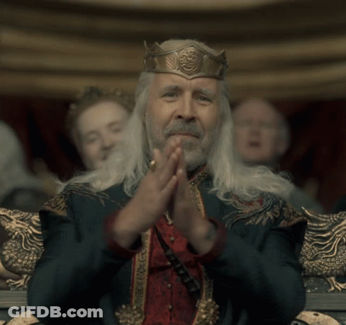 A Man With A Crown On His Head Is Clapping His Hands Together GIF