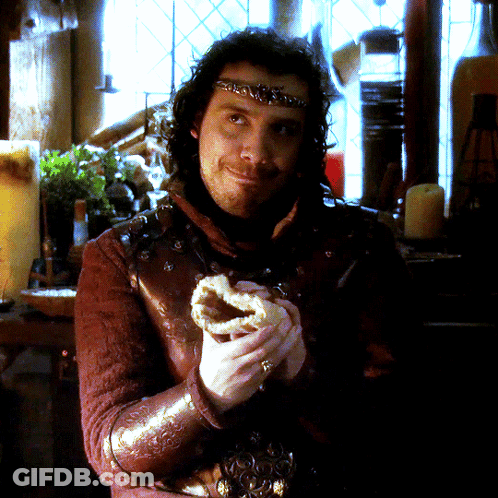 A Man With A Crown On His Head Is Holding A Pastry GIF