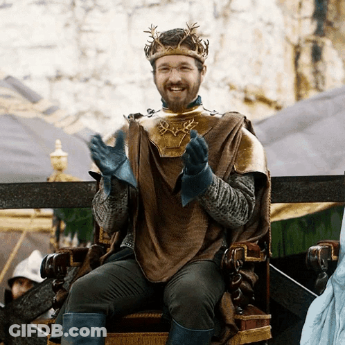 A Man With A Crown On His Head Is Sitting On A Chair GIF