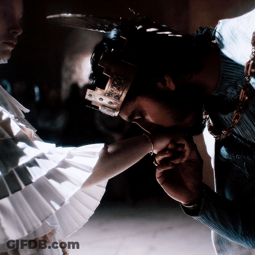 A Man With A Crown On His Head Kissing A Woman 'S Hand GIF