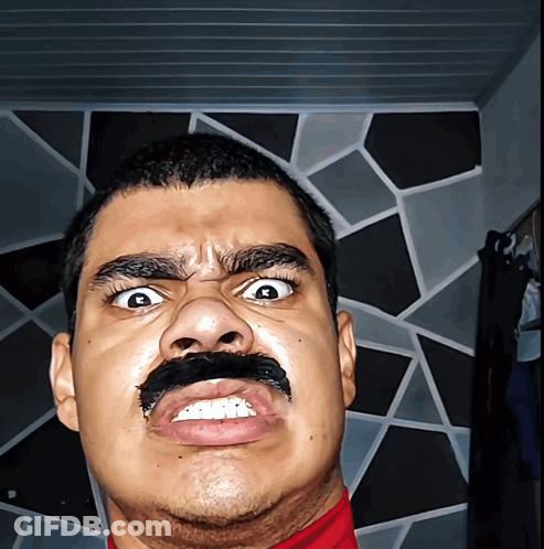 A Man With A Fake Mustache On His Face Makes A Funny Face GIF