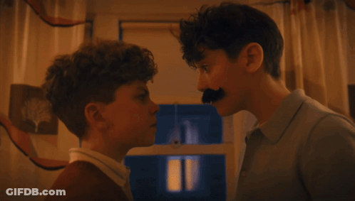 A Man With A Fake Mustache Touches The Nose Of Another Man GIF