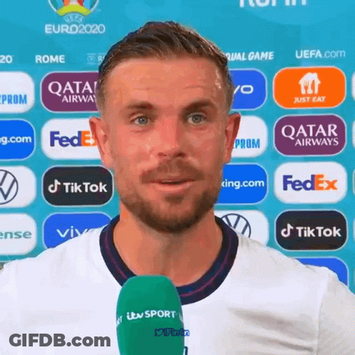 A Man With A Green Microphone In Front Of A Wall With Logos For Fedex And Qatar Airways GIF