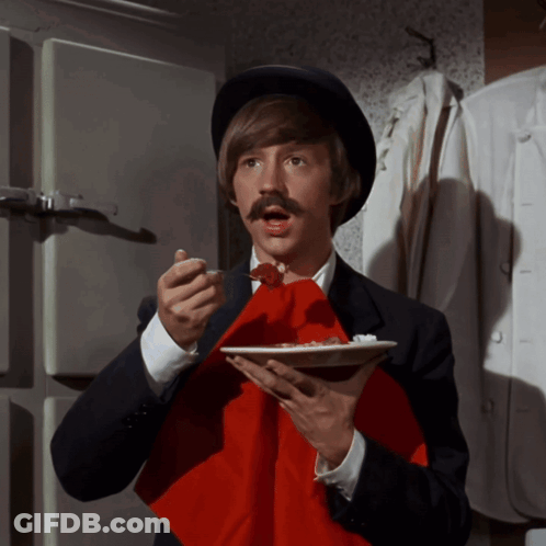 A Man With A Hat And Mustache Holds A Plate Of Food GIF