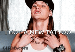 A Man With A Hat On Has A New Tattoo On His Chest . GIF