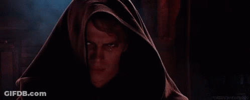 A Man With A Hood On His Head Is Looking At The Camera With A Serious Look On His Face . GIF