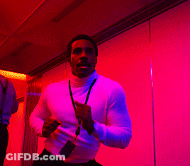 A Man With A Lanyard Around His Neck Is Running In A Room With Purple Lights GIF
