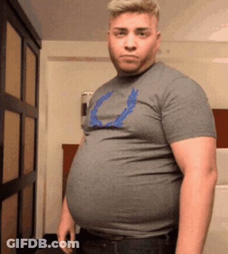 A Man With A Large Belly Is Wearing A Grey Shirt With A Blue Laurel Wreath On It . GIF