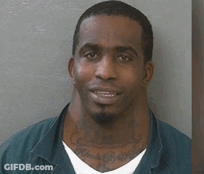 A Man With A Large Neck And A Tattoo On His Neck Is Smiling . GIF