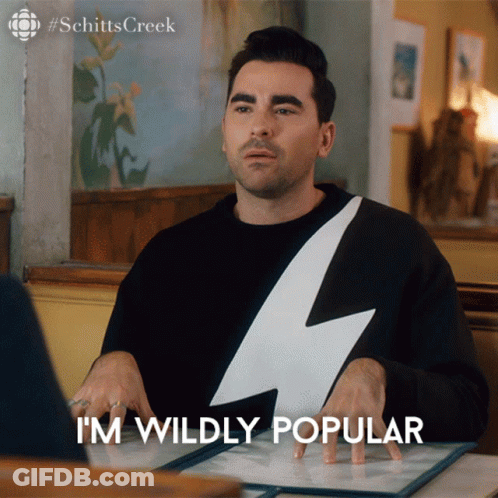 A Man With A Lightning Bolt On His Shirt Is Sitting At A Table And Says " I 'M Wildly Popular " GIF