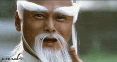 A Man With A Long White Beard And Eyebrows Is Making A Funny Face . GIF