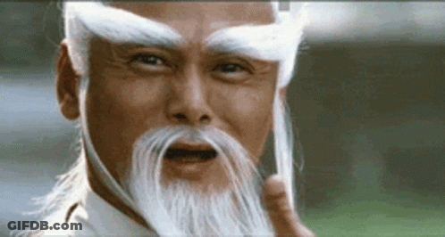 A Man With A Long White Beard And Eyebrows Is Making A Funny Face . GIF
