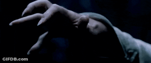 A Man With A Long White Beard Is Holding Something In His Hand In A Dark Room GIF