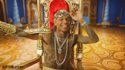 A Man With A Lot Of Tattoos Is Sitting In A Throne GIF