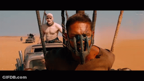 A Man With A Mask On His Face Is Driving A Car In The Desert GIF