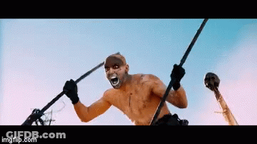 A Man With A Mask On His Face Is Holding A Spear And A Skull In His Hand .. GIF