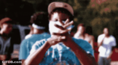 A Man With A Mask On His Face Is Making A Peace Sign . GIF