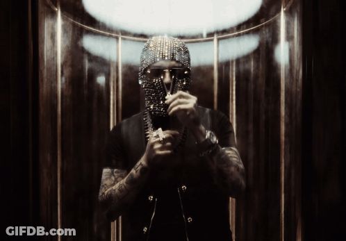 A Man With A Mask On His Face Is Standing In A Dark Room GIF