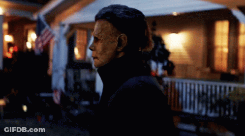 A Man With A Mask On His Face Stands In Front Of A House GIF