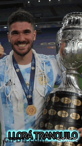 A Man With A Medal Around His Neck Is Holding A Trophy And Says Llora Tranquilo GIF