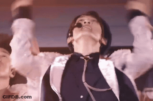 A Man With A Microphone In His Mouth Is Dancing On A Stage . GIF