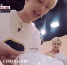 A Man With A Microphone On His Ear Is Holding A White Object In His Hands . GIF
