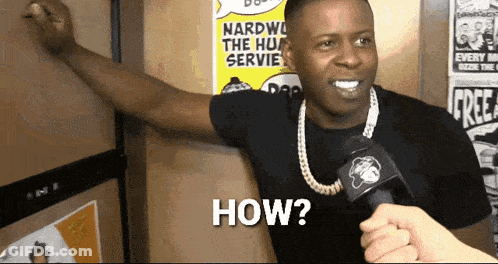 A Man With A Microphone Says How In Front Of A Wall With Posters On It GIF