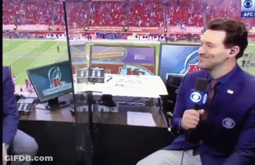 A Man With A Microphone Sitting In Front Of A Screen That Says Champions On It GIF