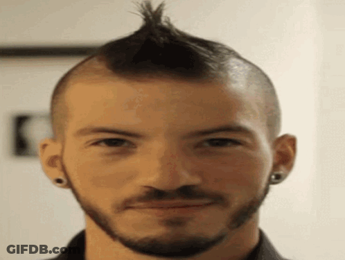 A Man With A Mohawk And A Beard Is Smiling . GIF