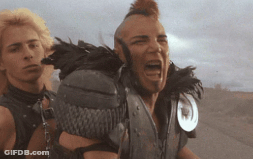 A Man With A Mohawk And Feathers On His Shoulder Screams GIF