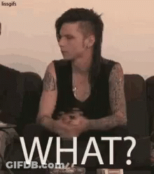 A Man With A Mohawk Is Sitting On A Couch With The Words `` What ? '' Written On It . GIF