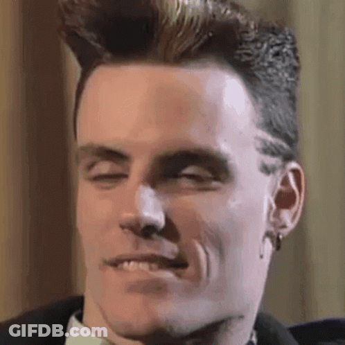A Man With A Mohawk Is Smiling With His Eyes Closed . GIF