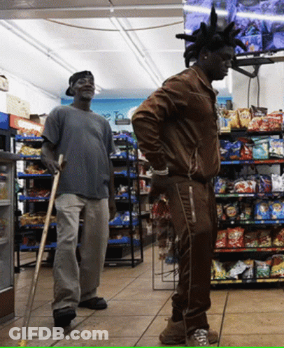 A Man With A Mohawk Stands In A Store Next To Another Man GIF