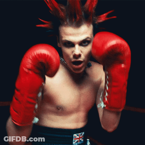 A Man With A Mohawk Wearing Red Boxing Gloves And A British Flag Belt GIF