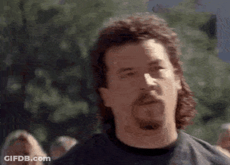 A Man With A Mullet And A Beard Is Wearing A Black Shirt . GIF