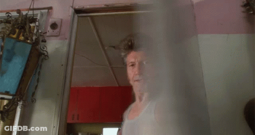 A Man With A Mullet And A Tank Top Stands Next To A Woman GIF