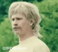 A Man With A Mullet And Mustache Is Wearing A White Shirt And A Wig . GIF
