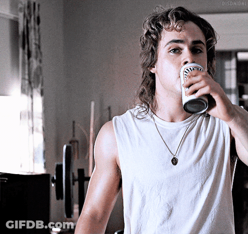 A Man With A Mullet Is Drinking From A Can That Says Budweiser On It GIF