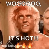 A Man With A Mullet Is Holding A Microphone And Says `` It 'S Hot ! '' GIF