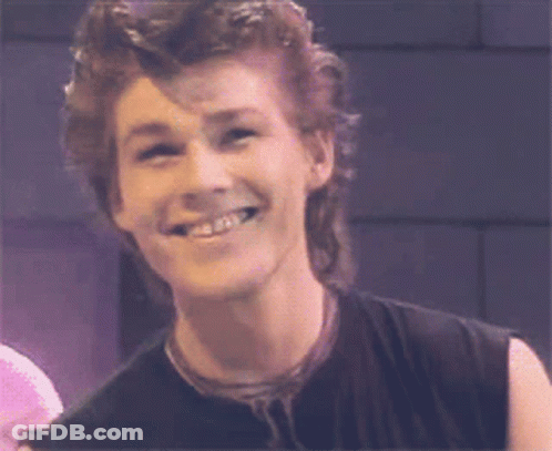 A Man With A Mullet Is Smiling And Wearing A Black Shirt GIF