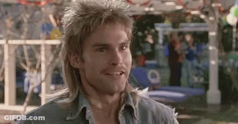 A Man With A Mullet Is Smiling And Wearing A Blue Shirt . GIF