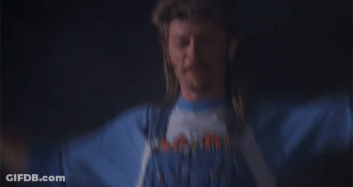 A Man With A Mullet Wearing A Blue Shirt That Says ' Mountain ' On It GIF