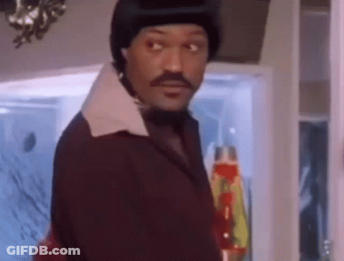A Man With A Mustache And A Hat Is Standing In Front Of A Window . GIF
