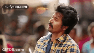 A Man With A Mustache And A Plaid Shirt Is Standing In A Crowd . GIF