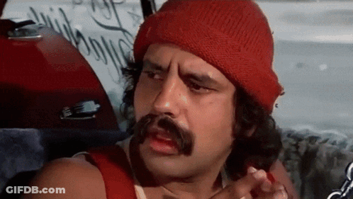 A Man With A Mustache And A Red Beanie Is Sitting In The Back Seat Of A Car . GIF